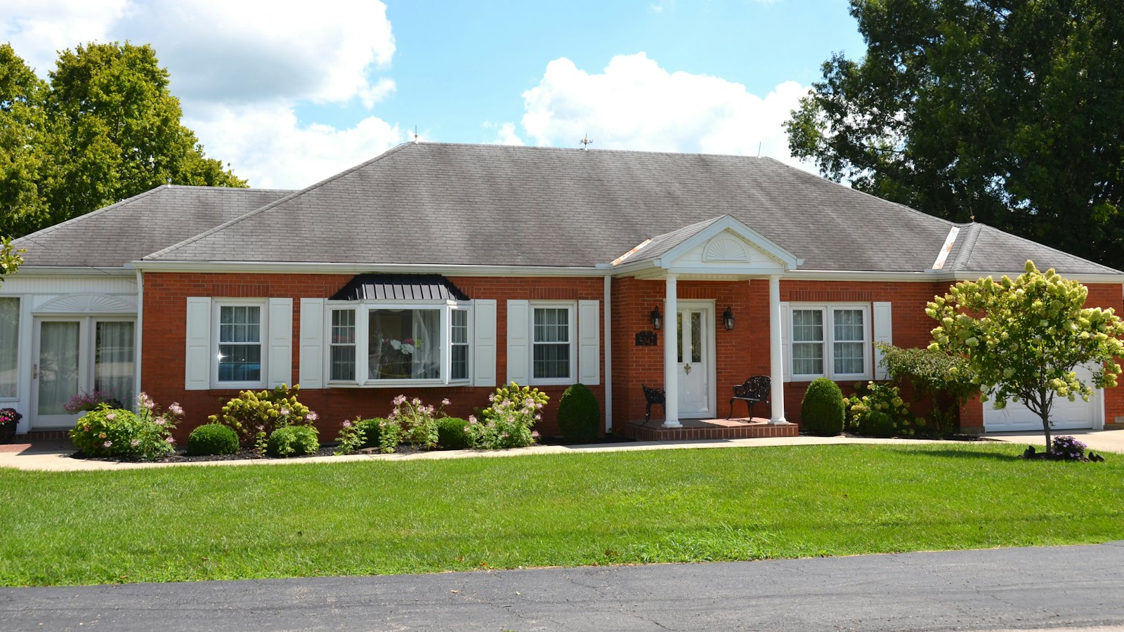 A well kept red brick ranch house with a broad green front lawn, the kind of maintained Greater Cincinnati yard a mole can cross in a single night