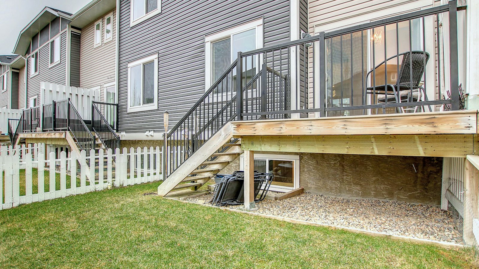 A backyard deck raised well off grade with the open space underneath left unskirted, the kind of dry sheltered cavity a raccoon dens in